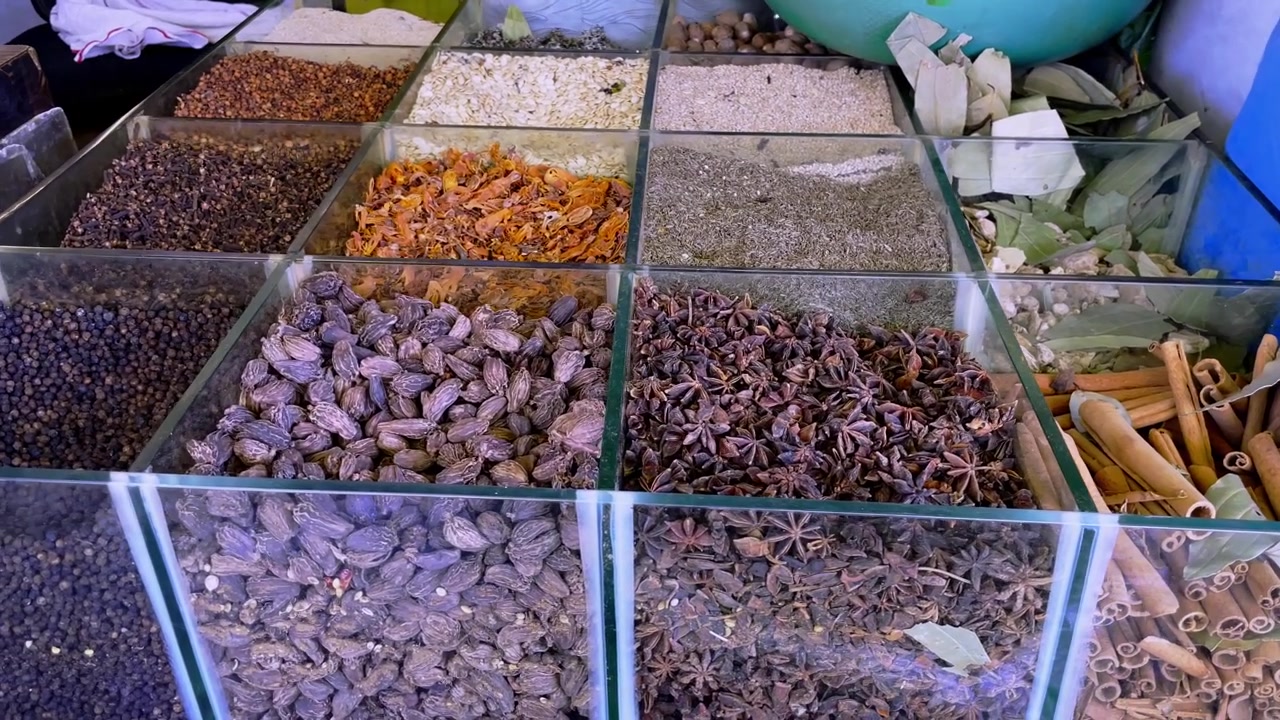 Vista em close-up de especiarias indianas variadas exibidas em recipientes de vidro em uma loja de mercado tradicional em Indore, Madhya Pradesh, Índia, mostrando ingredientes usados na culinária indiana e no comércio de especiarias.
