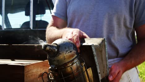 beekeeper preparing bee smoker on truck