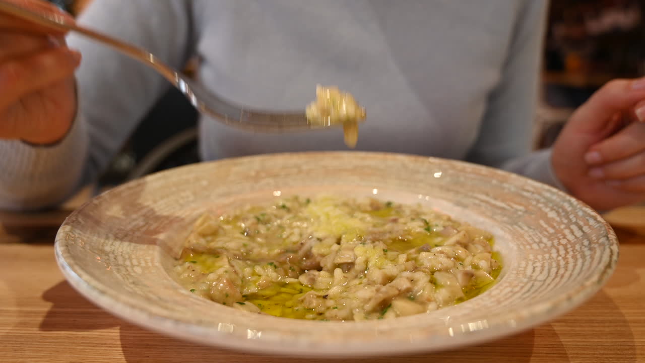 Woman eating risotto with mushrooms in a restaurant