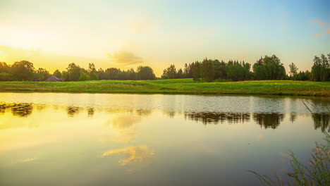 Cinematic-timelapse-of-the-sunrise-over-a-lake-with-trees-and-fine-grass-on-the-shore-on-a-sunny-and-cloud-free-day,-Time-Lapse