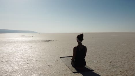 woman teacher doing meditation pose on the lake tuz, salar in turkey