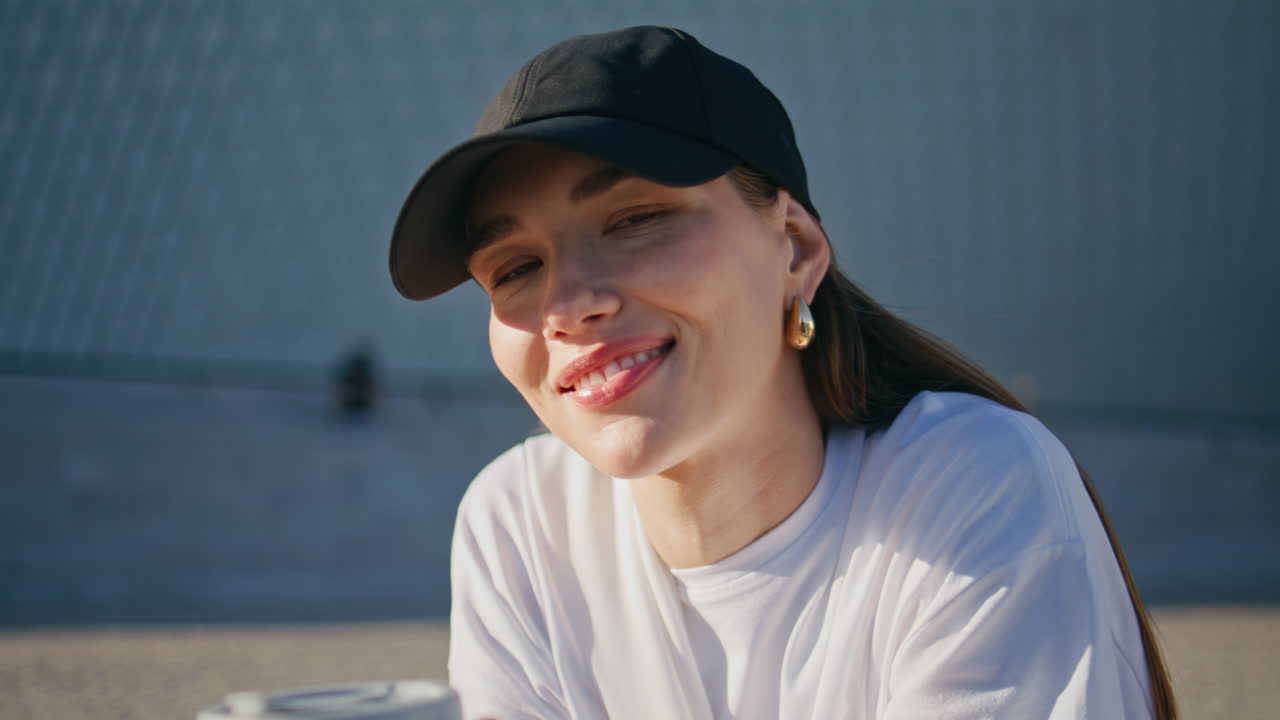 Portrait dreamy model sitting sunny street area holding coffee cup. Smiling girl