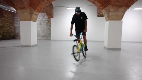a bmx sport rider, riding inside of a warehouse doing tricks - follow shot