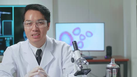 Asian Scientist In The Laboratory With A Microscope And Speaking To The Camera