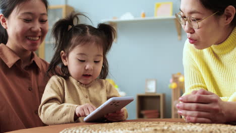 Asiatische-Frauen-Mit-Einem-Baby-Sitzen-An-Einem-Tisch