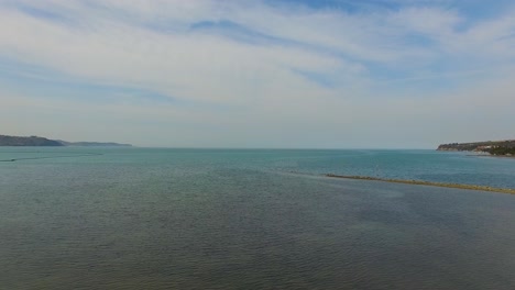 high view of the gulf of trieste in the adriatic sea in the direction of venice italy at the pokopalisce skoljk beach, solvenia, aerial drone rise-up shot
