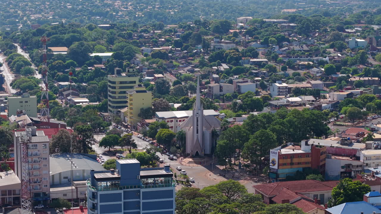 Slow general drone shot passing over city buildings and approaching San Antonio Cathedral. Multiple trees and vegetation around city streets. Shot on 4K at 60fps