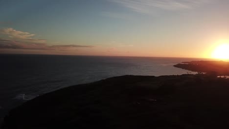 sunset drone pan in kauai with rainbow, mountain, and ocean