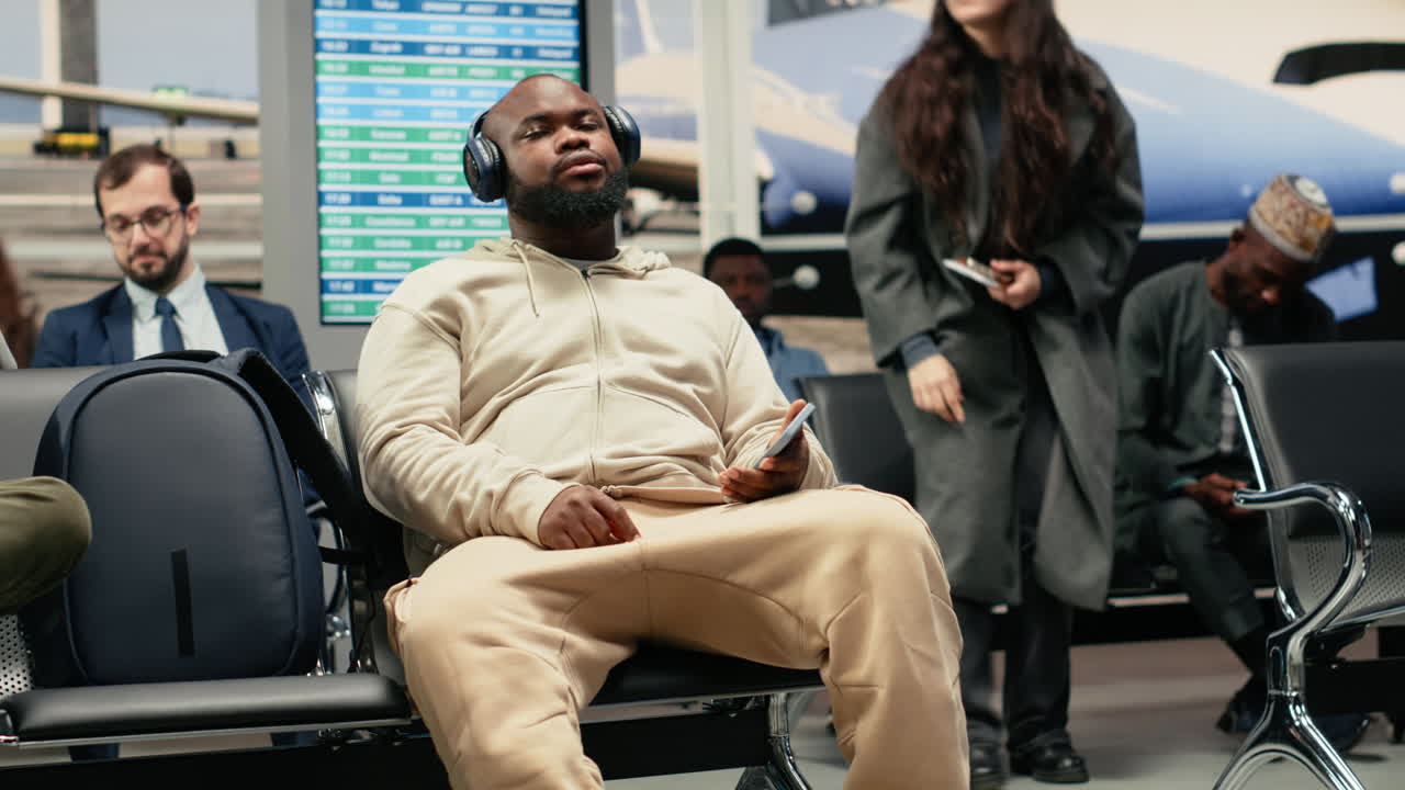 Relaxed man in airport listening music with smartphone, going to sleep