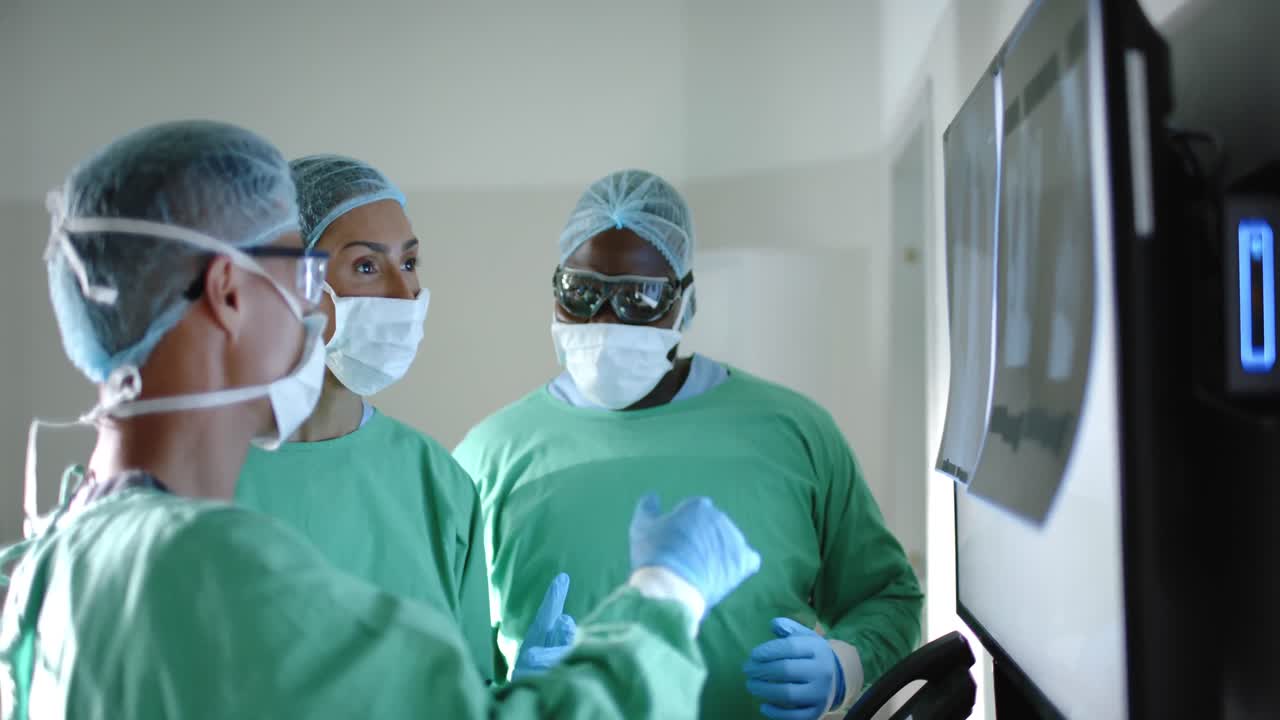 Seri chirurghi diversi con mascherine chirurgiche che esaminano una radiografia in sala operatoria al rallentatore