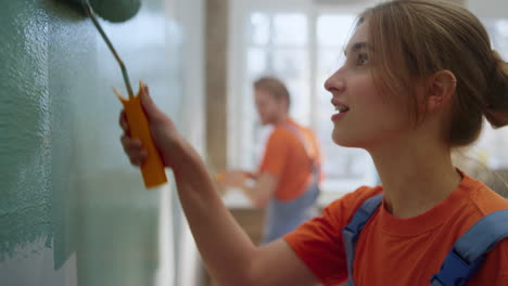 happy couple painting wall indoors. family dancing during home repair in house.