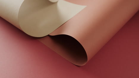 Close-up-of-two-shades-of-brown-rolled-papers-on-red-background-with-copy-space-in-slow-motion