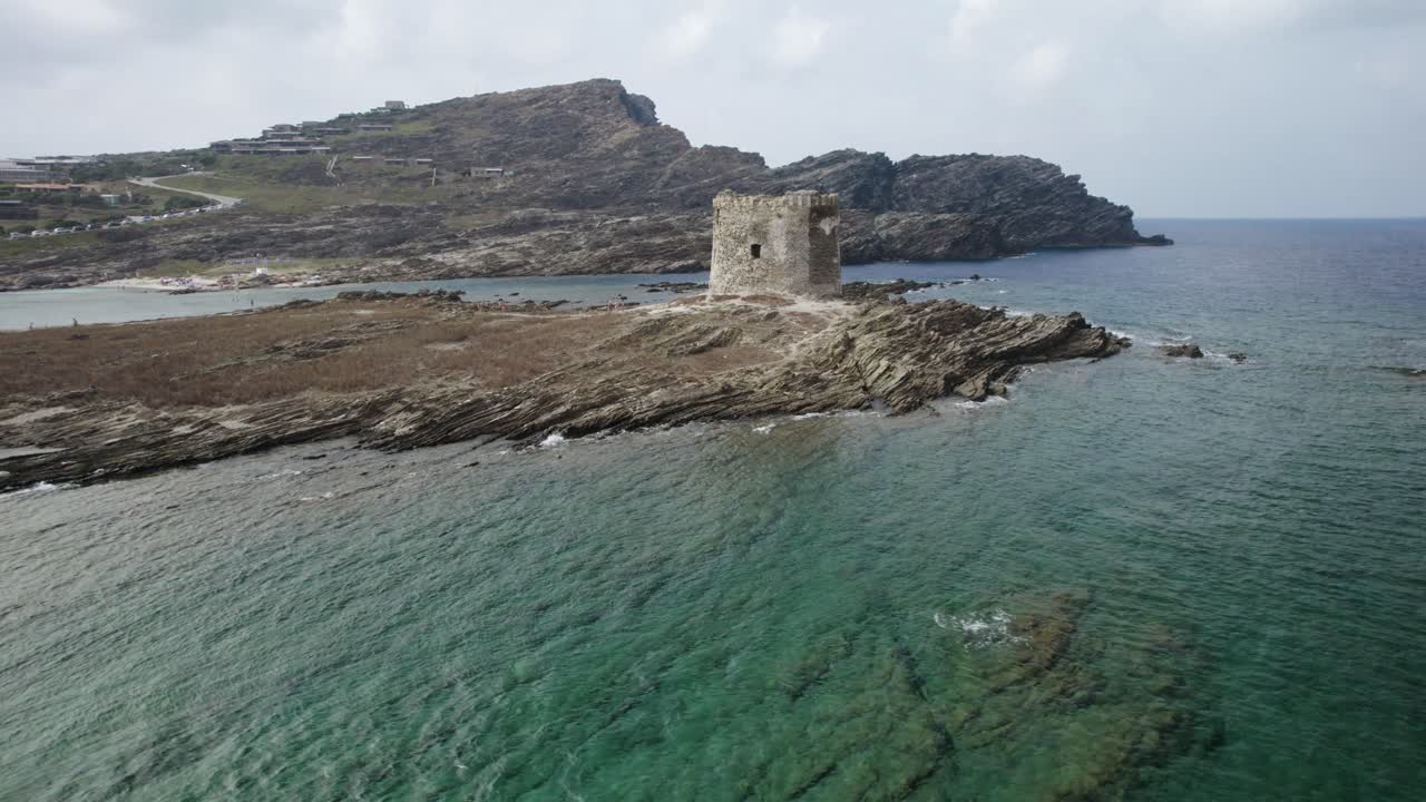 órbita aérea rápida de baja altitud sobre la atalaya medieval de pelosa en la isla rocosa rodeada por el mar esmeralda