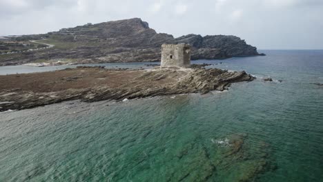 órbita aérea rápida de baja altitud sobre la atalaya medieval de pelosa en la isla rocosa rodeada por el mar esmeralda