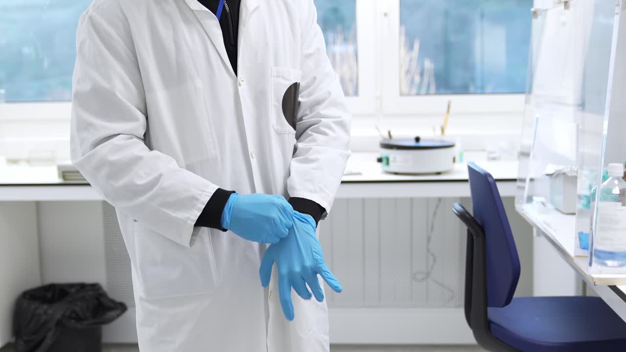Vědec si nasazuje ochranné rukavice v laboratoři