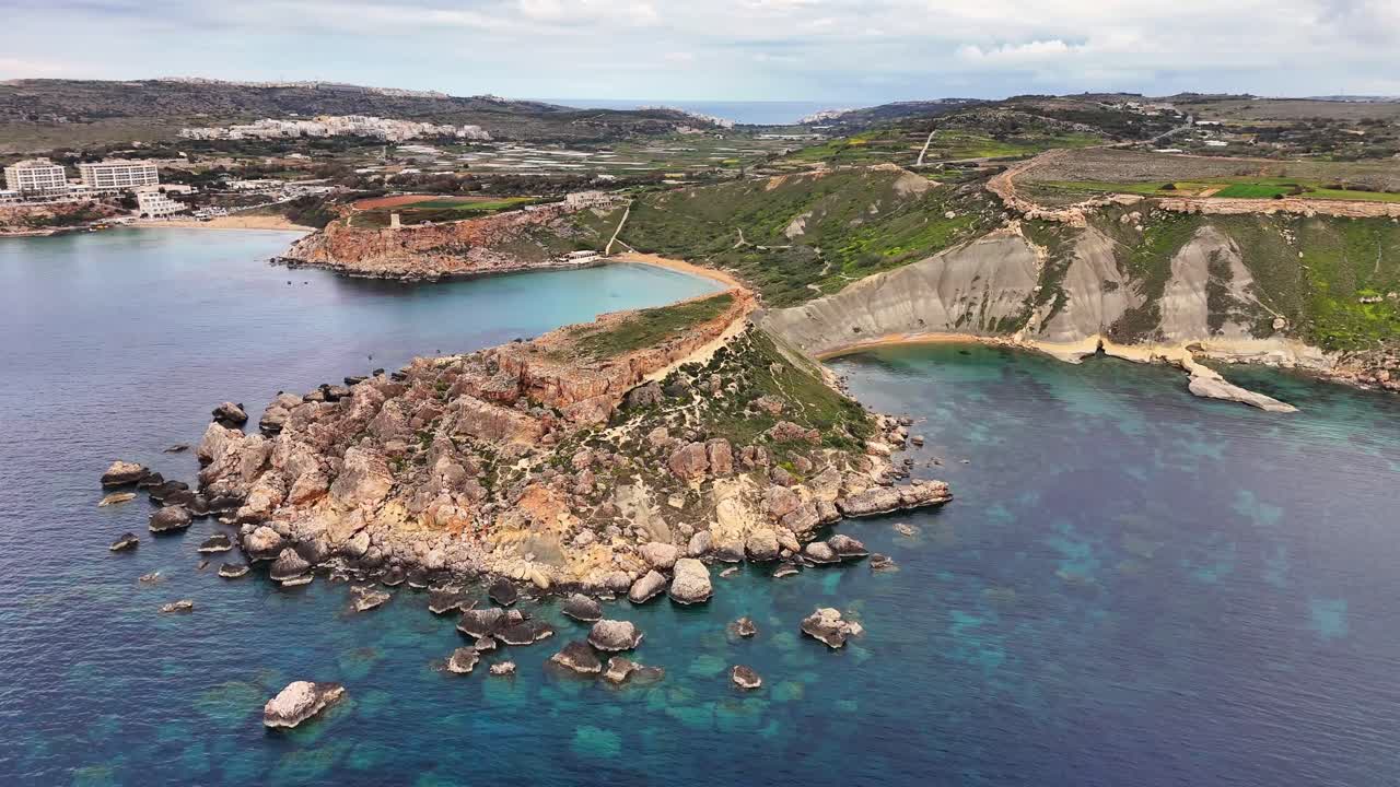 Vista aerea con drone della Baia di Qarraba a Malta con ripide scogliere calcaree, costa rocciosa e acqua turchese cristallina che forma piccole insenature lungo la costa frastagliata di giorno.