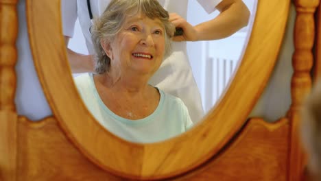 doctor combing senior woman hair on dressing table 4k