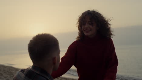 smiling woman running to man on beach. couple kissing on sea coast at sunset