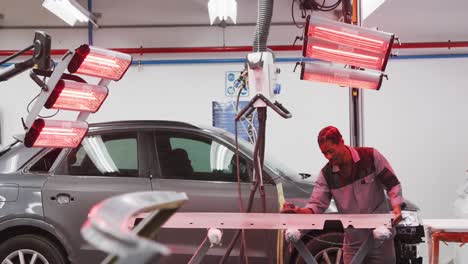 mecánico de automóviles afroamericano usando un molinillo en una pieza de un automóvil