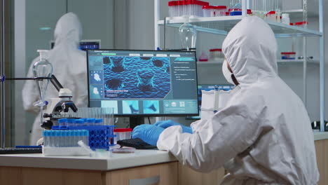 científico médico en traje de ppe trabajando con imagen de escaneo de adn