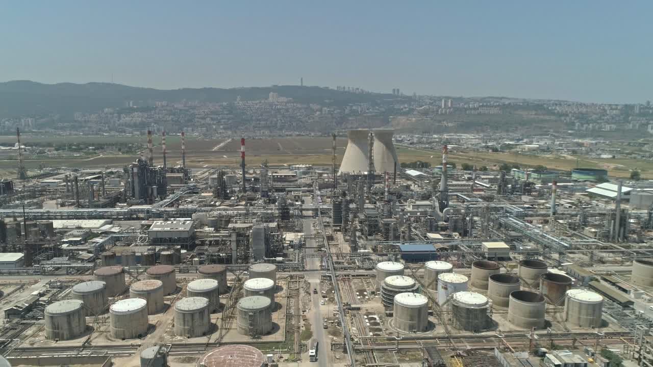 Aerial footage of a large scale Oil refinery with smoke stacks and petroleum storage tanks