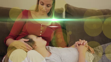 animation of light and dots moving over happy caucasian mother and daughter on sofa talking