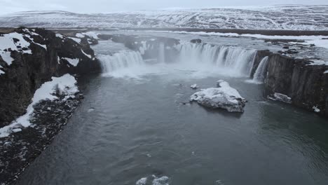 Scenic-waterfall-streaming-from-rocky-cliff-on-winter-day