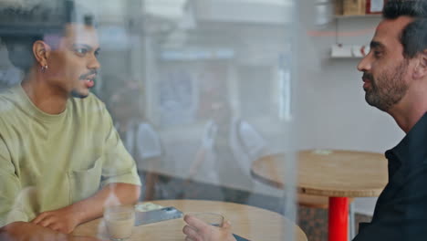 couple male friends meeting in cozy cafe close up. two guys talking laughing