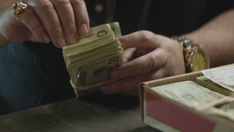 a mafioso man counting a stack of cash