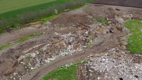 abandoned structures next to a garbage hill on landfill and workers in not recycling trash