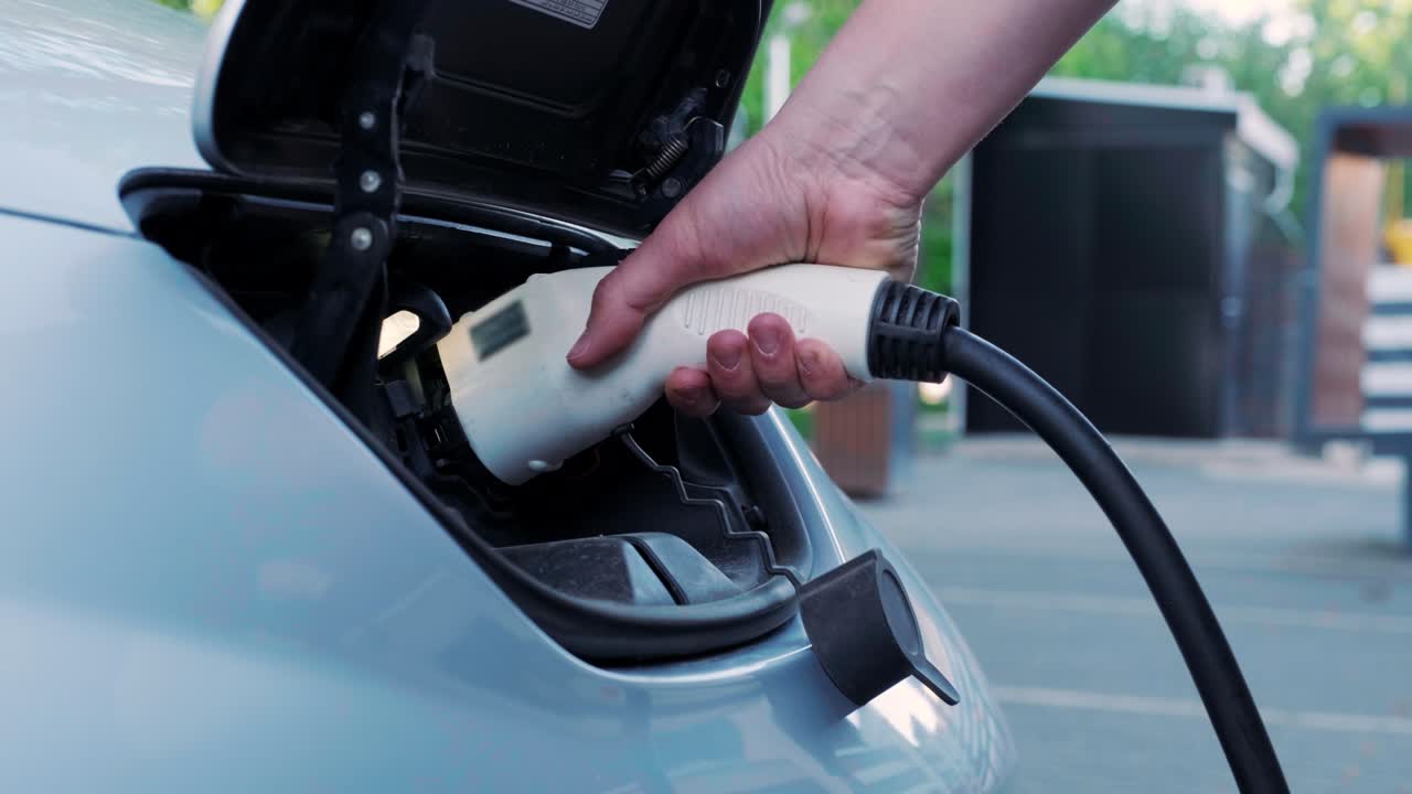 proceso de reabastecimiento de combustible de un automóvil eléctrico. un disparo debajo de la escotilla donde se carga el automóvil ecológico eléctrico. la escotella de carga del automóvil eléctrico se abre automáticamente. una mano masculina inserta un automóvil erecto