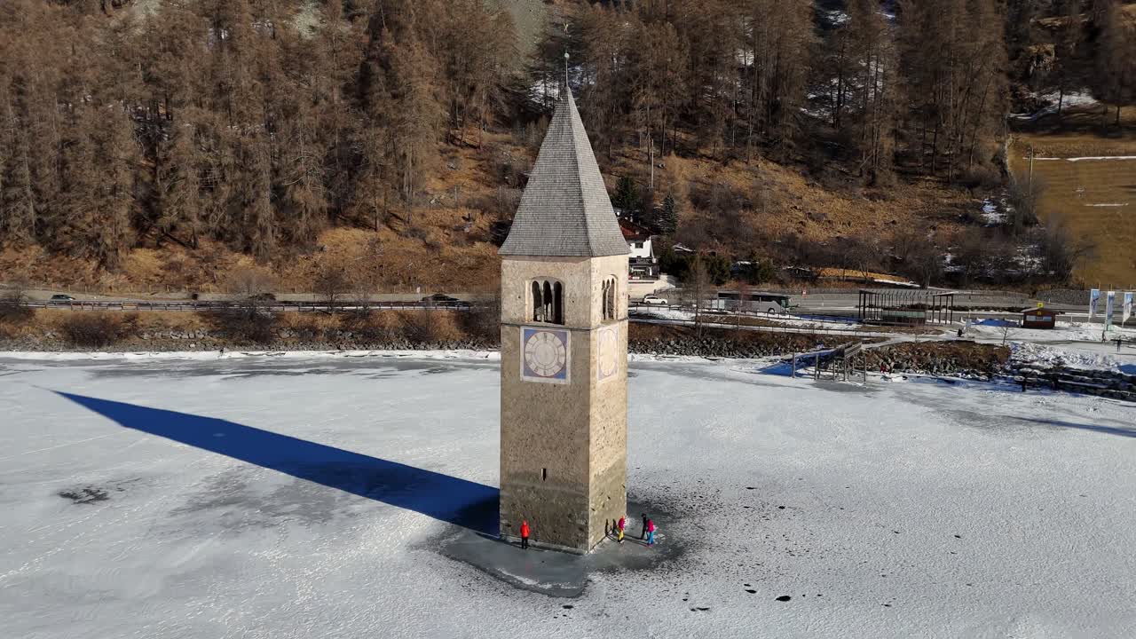 Bell tower in the Italian Alps in frozen lake during the winter season (drone footage)