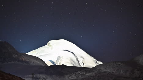 timelapse: el cielo estrellado oscuro se mueve detrás de una montaña de hielo en los alpes suizos