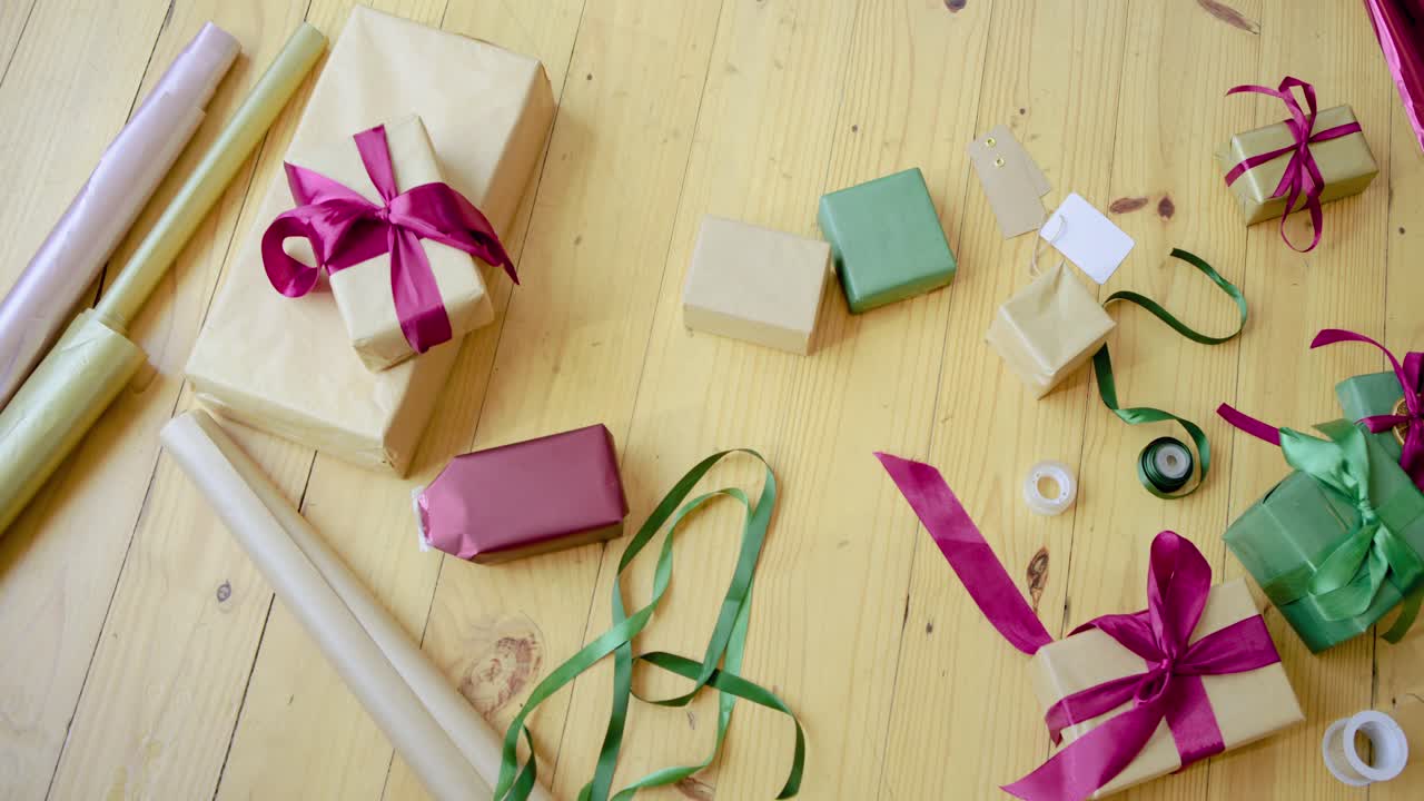 La cámara empieza una panorámica lenta sobre los materiales para envolver regalos en la mesa, revelando los detalles del proyecto