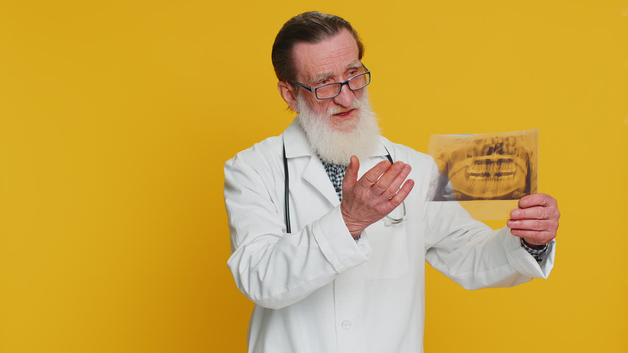 Senior doctor orthodontist man examines a panoramic xray picture of the jaw teeth stomatology