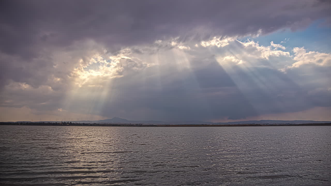 los rayos del sol brillan a través de las nubes sobre el lago salado de larnaca en chipre - lapso de tiempo
