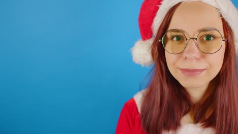 mujer con disfraz de papá noel y gafas sobre fondo azul con espacio para el texto. mujer con sombrero de navidad, gafas mirando a la cámara y sonriendo. pancarta. chromakey