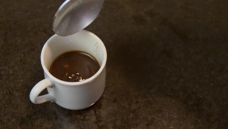 putting some white sugar in delicious moka coffee in the morning - close up