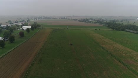 Drone-Ariel-Vista-De-Tierras-Agrícolas-Amish-Y-Granjero-Amish-Cosechando-En-La-Niebla