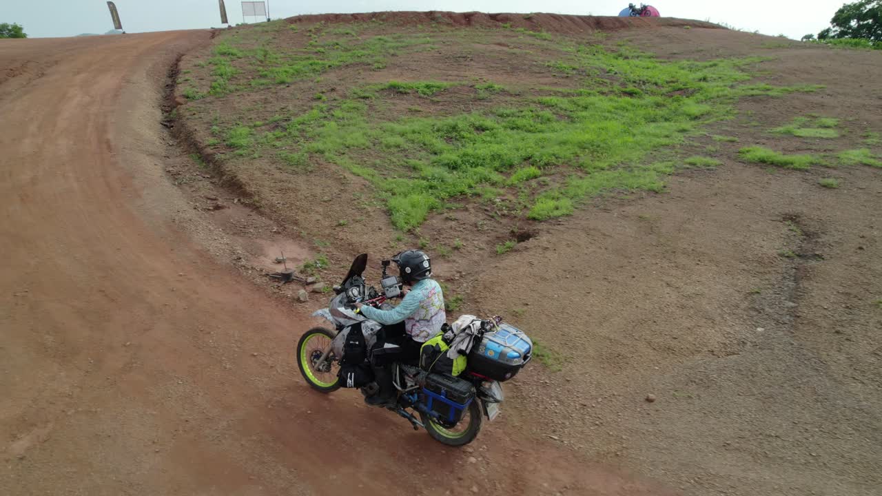 Adventurer on motorcycle riding a winding dirt road in the countryside, South AMerica