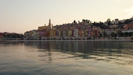 Atemberaubender-Sonnenuntergang-An-Der-Küste-Von-Menton,-Frankreich---Luftdrohnenanflug-Auf-Farbenfrohe-Gebäude