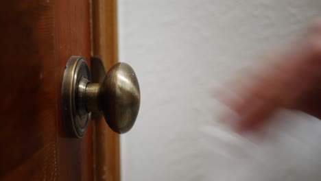 cleaning and sanitizing a door knob covered in germs and corona virus with a disinfecting antibacterial wipe in a home to stay healthy and safe during pandemic