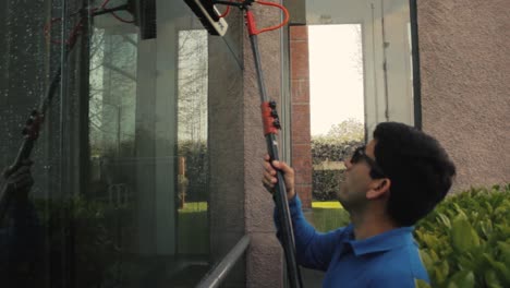 camera beside, cleaning a big glass with a pole with pure water system