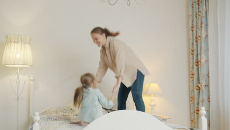 mother and daughter jumping on bed