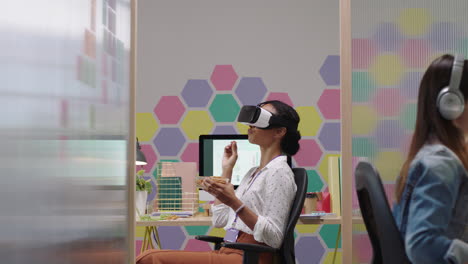 mujer de negocios feliz con auriculares de realidad virtual disfrutando del entretenimiento en la pausa del almuerzo comiendo pretzels en un colorido lugar de trabajo de oficina moderno