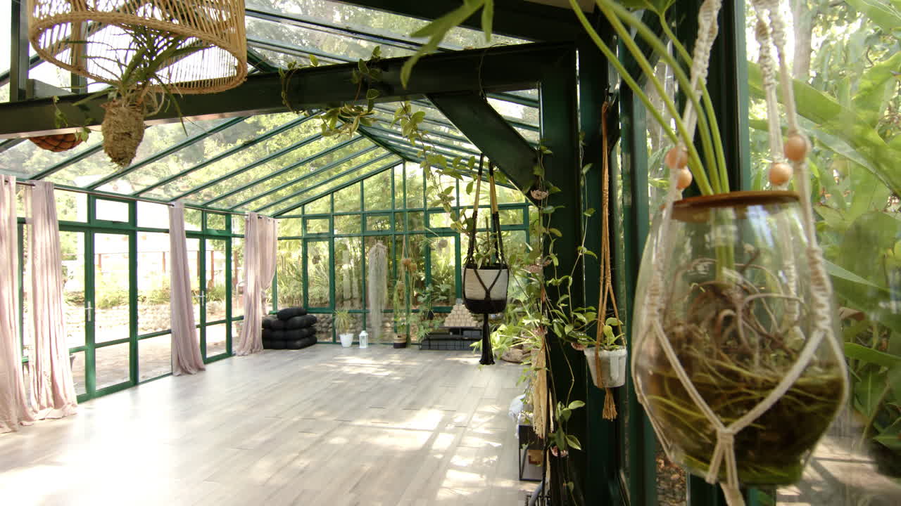 Empty glass house with hanging plants, ready for yoga session, copy space
