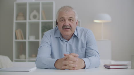 middle-aged blogger is greeting followers and starting webinar waving hand looking at camera portrait from webcam of laptop