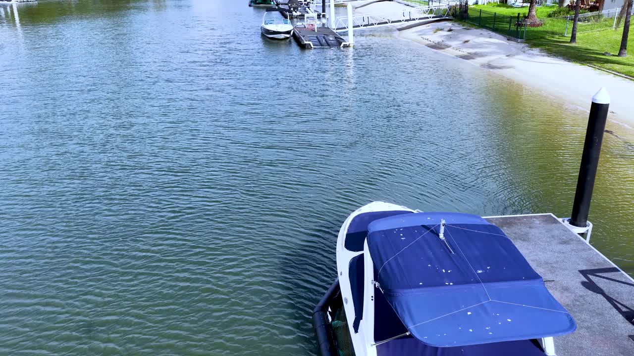 Aerial view of luxury boat leaving marina dock, sunny daylight, smooth camera movement, coastal setting