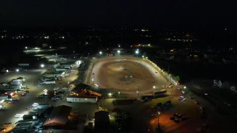 multiple aerial orbits of oval dirt race track racing at night