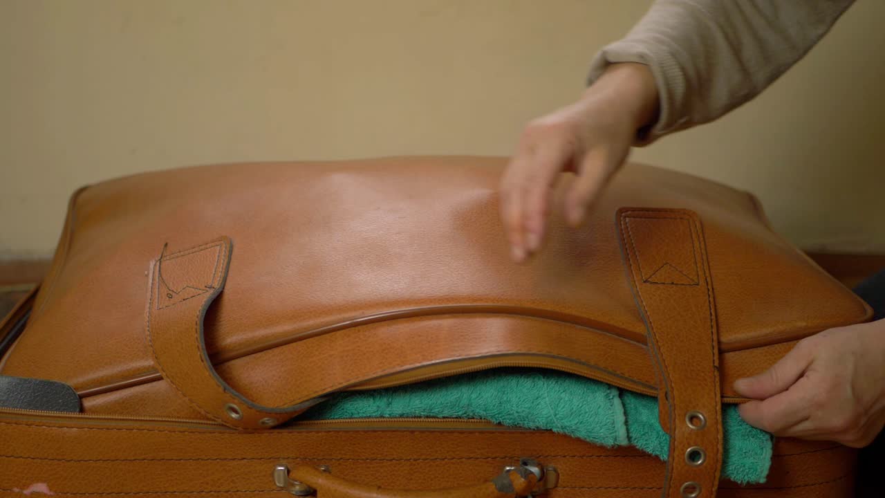 Parent closing suitcase filled with clothes and toys close up shot